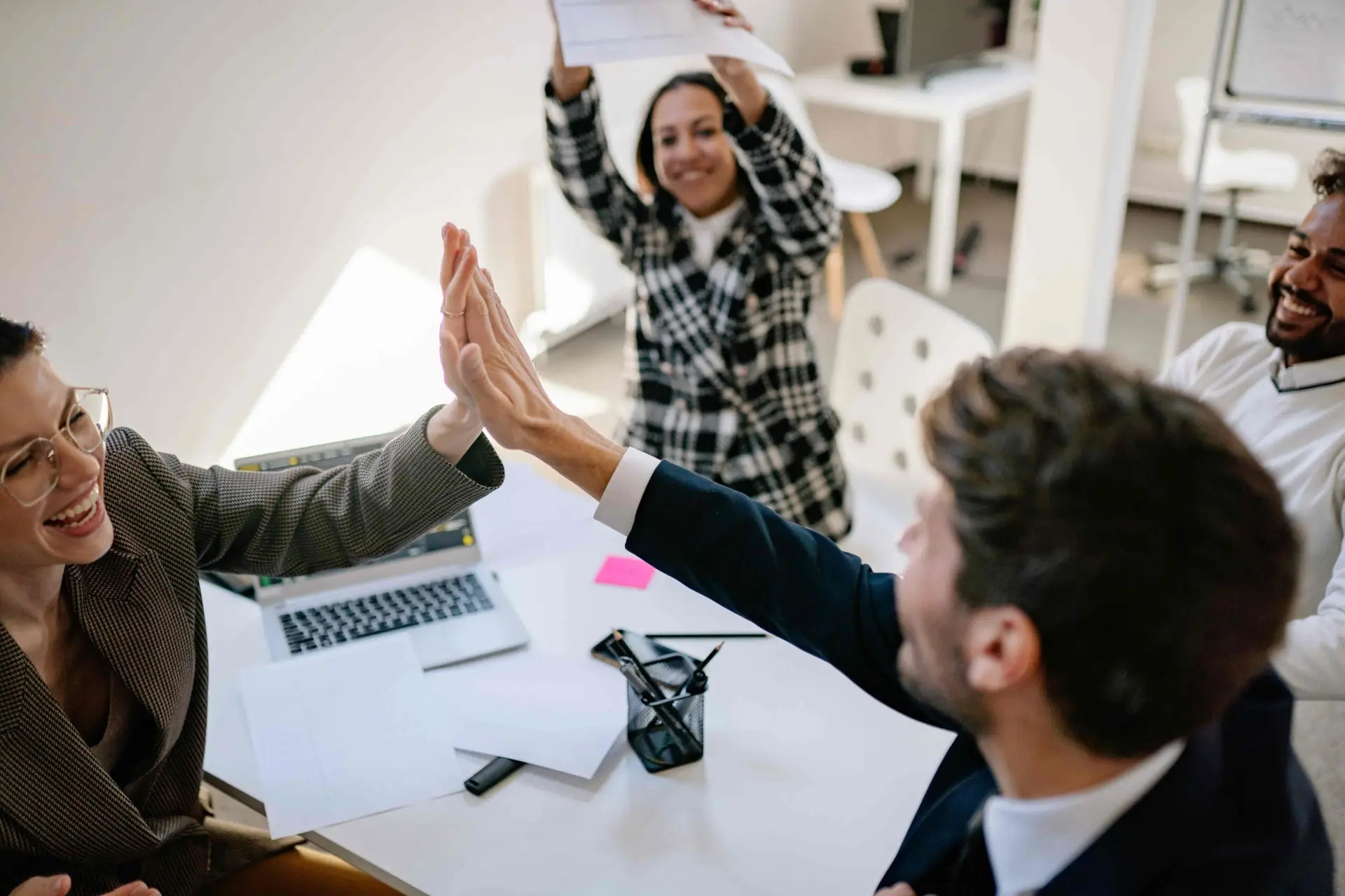 Group of workers and leaders celebrating success with two people high fiving.