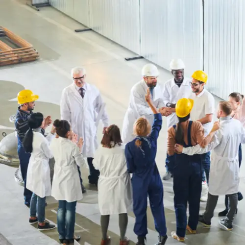 a group of frontline workers having a meeting on the factory floor
