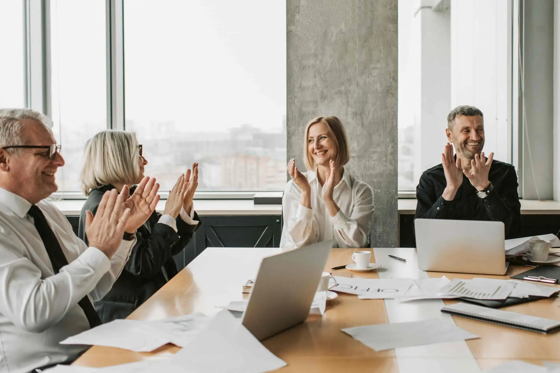 Workers celebrating a successful change in an office with a tall glass window in the background
